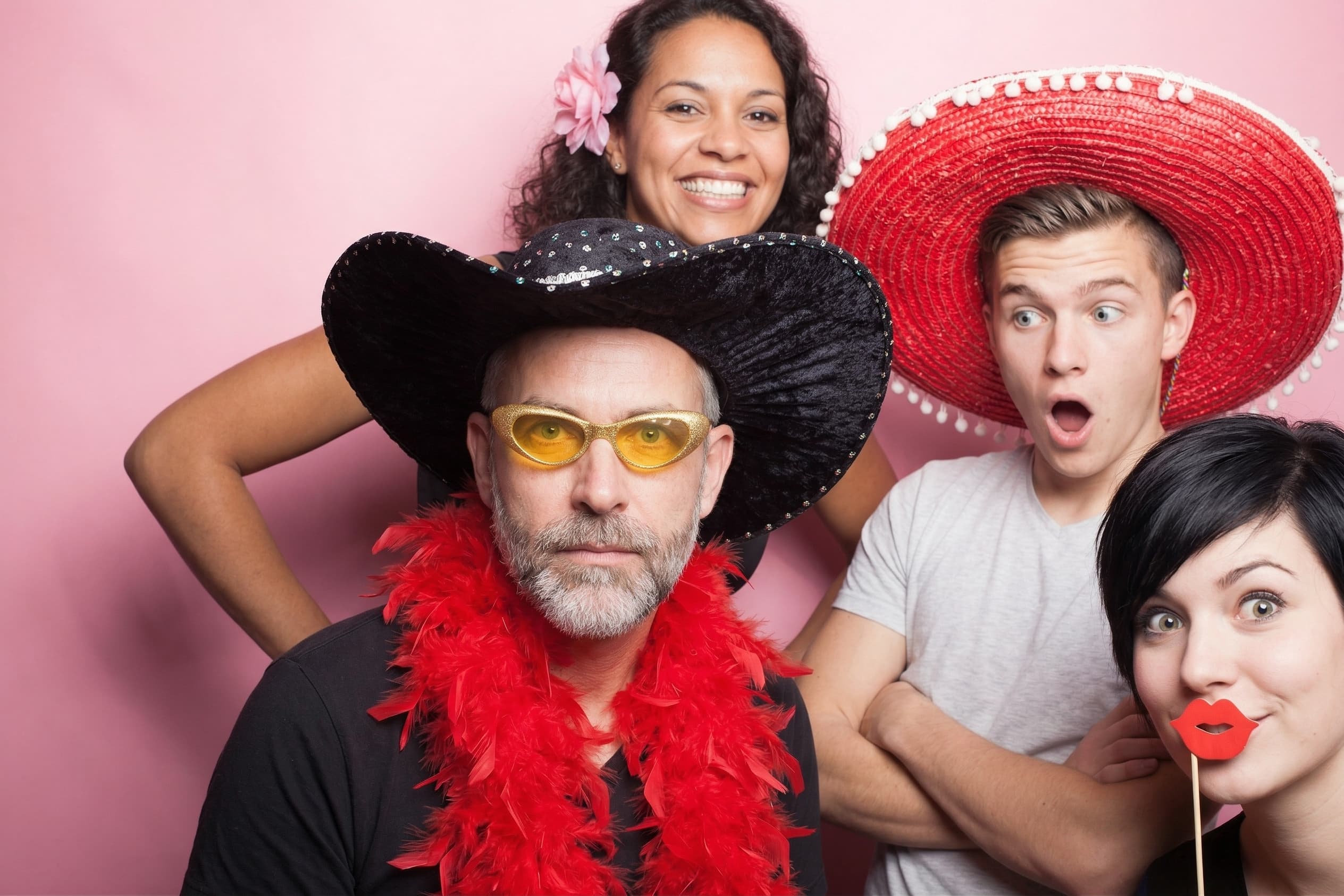Gruppe posiert ausgelassen in der Fotobox mit Hüten, Sonnenbrille und Federboa